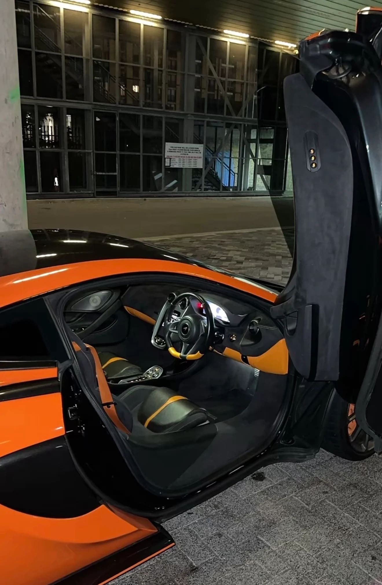 Orange McLaren supercar interior with butterfly door open at night